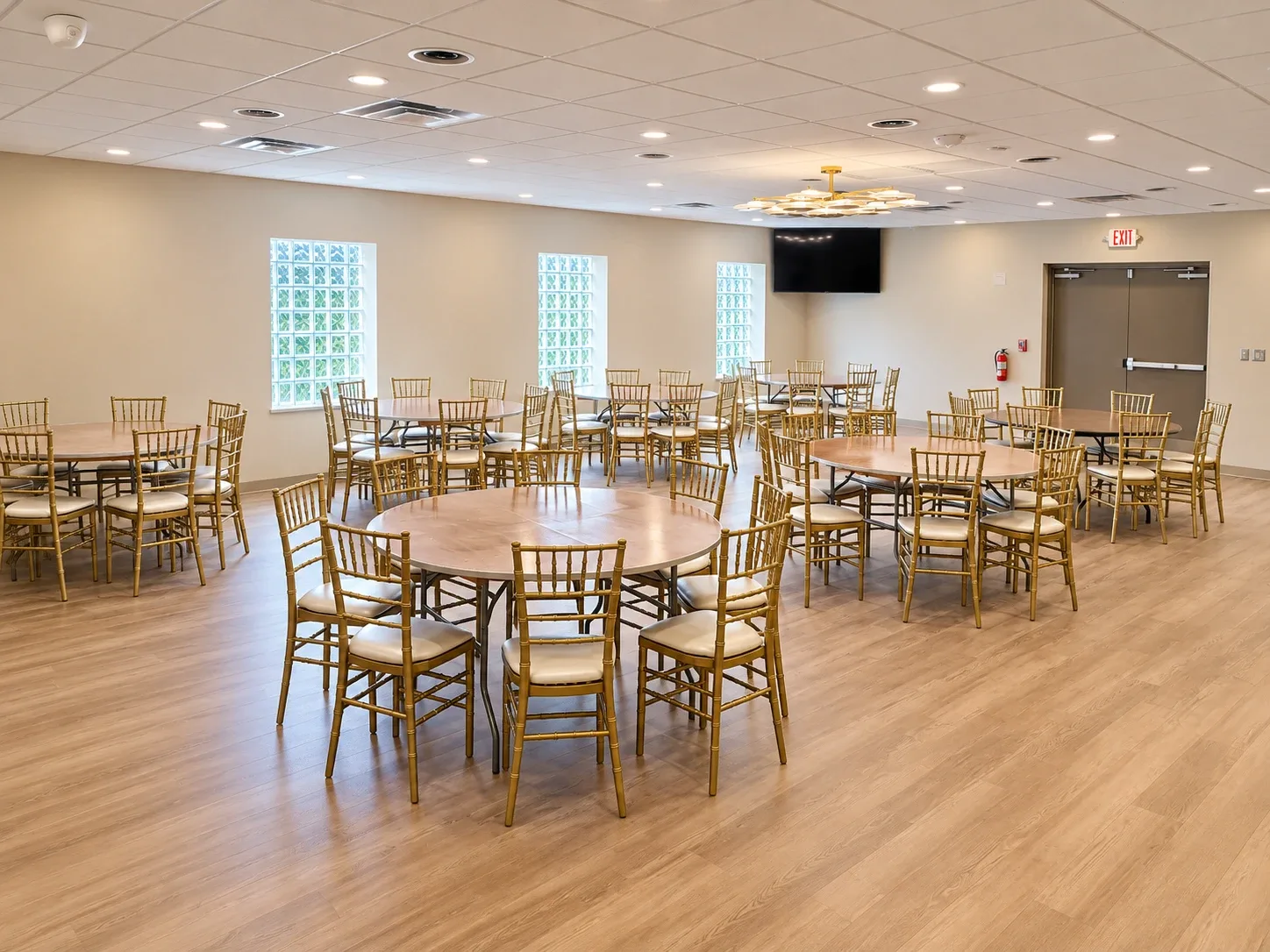 The hall set with round tables and gold chairs, seen from the far corner.
